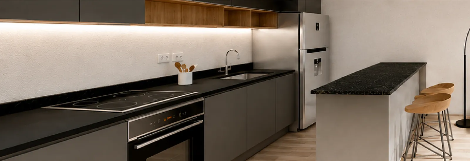 Fitted kitchen with cooktop, oven and dark countertop